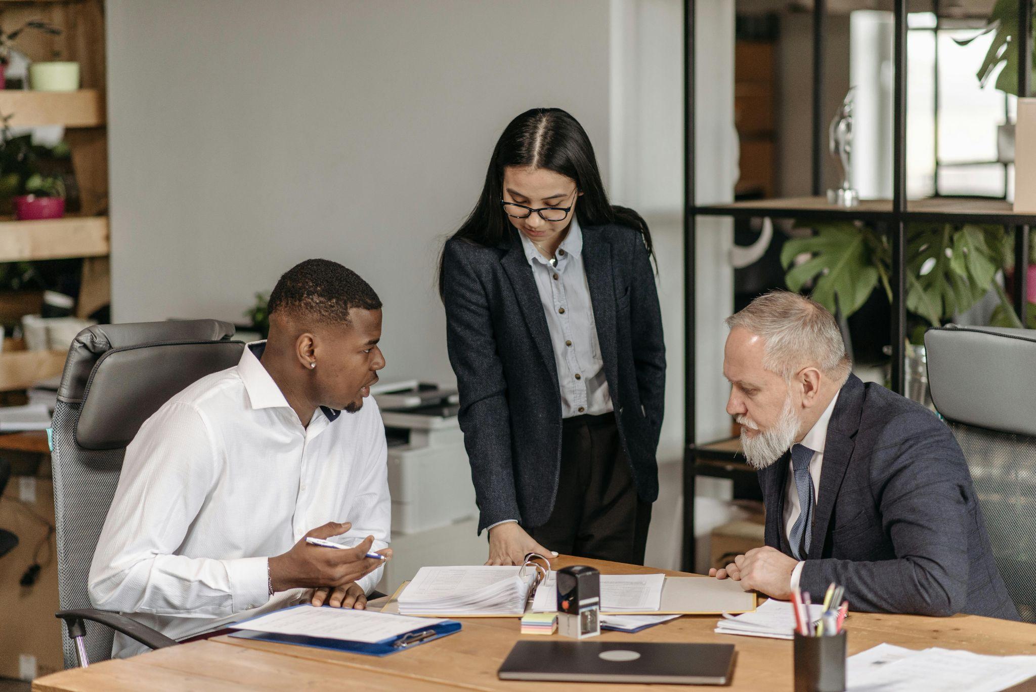 A woman and two men discussing compensation decisions for a multi-location workforce